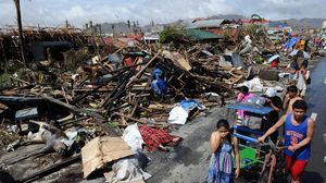 مواطنون يسيرون بجانب جثث لضحايا إعصار هايان في الفلبين - أ ف ب