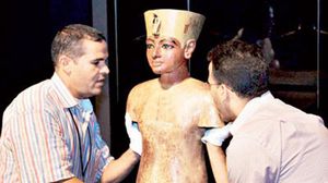 تمثال توت عنخ آمون يحمله عاملان في المتحف القومي المصري - رويترز