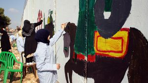 طفلة يتيمة تقوم بتلوين الجدار الفاصل بين لبنان والكيان الإسرائيلي - الأناضول