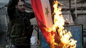 مقاتل من المعارضة يحرق علم النظام السوري (ارشيف - ا ف ب)