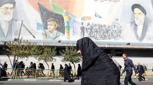 سيدة إيرانية تسير بجانب جدارية لمرشدي الثورة الإيرانية الخميني والخامنئي- جيتي