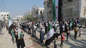 حمل المشاركون في الوقفة لافتات كتب عليها بالعربية والانكليزية "العودة تبدأ برحيل الأسد"- الأناضول