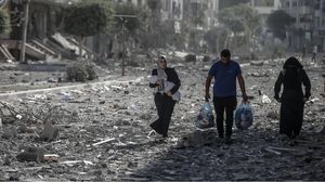 سيدة تحمل رضيعها وتمشي مع أقاربها وسط الأنقاض في حي تل الهوا بغزة المصدر: الفايننشيال تايمز