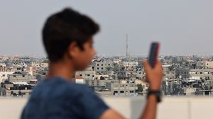 شاب من غزة يصعد على بناية مرتفعة أملا في التقاط الشبكة- جيتي