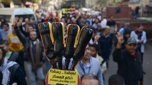 متظاهر يرفع شعار رابعة وعليه عبارة "يسقط حكم العسكر" خلال مظاهرات "جمعة إسقاط استفتاء الدم" (الأناضول)