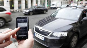 تطبيق "أوبر" على هاتف ذكي أمام سيارة أجرة في باريس - أ ف ب