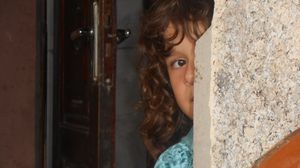 طفله فلسطينية تتوارى بجدار بيتها المدمر - عربي21