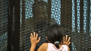 طفلة أحد المعتقلين تحاول الحديث مع والدها من خلف شبك الزنزانة داخل محكمة- الأناضول