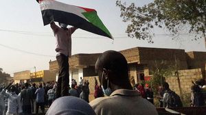 شاب سوداني يرفع العلم في إحدى التظاهرات- جيتي