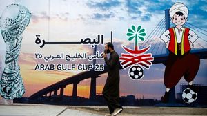 أحد المشاركين في البطولة يسير بجانب لوحة تحمل عبارة كأس الخليج 25- جيتي