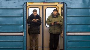 راكبان يستخدمان خدمة الواي فاي المجانية بقطار الأنفاق بموسكو - أ ف ب
