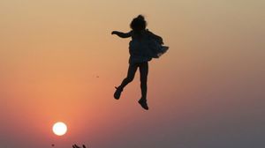رجل يلقي فتاة إلى الأعلى في أثناء غروب الشمس في منطقة القرم ـ روسيا اليوم