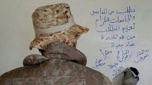 أحد عناصر حزب الله يخط عبارات حزبية على جدار مدرسة- أرشيفية