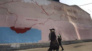 سيدة روسية تسير أمام جدارية لخارطة شبه جزيرة القرم- جيتي