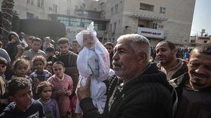 فلسطيني يرفع جثمان حفيده الرضيع الذي استشهد اليوم- تويتر