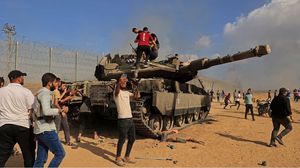 فلسطينيون يعتلون دبابة مدمرة خلال عملية طوفان الأقصى- جيتي