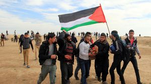 فلسطينيّون ينقلون مصاباً برصاص جيش الاحتلال على حدود غزة - الأناضول