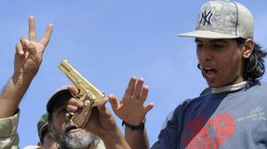 محمد البيبي يمسك بمسدس القذافي المطلي بالذهب - أرشيفية