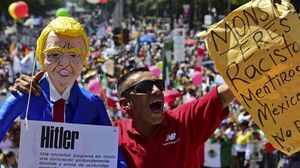 محتج مكسيكي يحمل مجسما لترامب يحمل لافتة باسم "هتلر"- أ ف ب