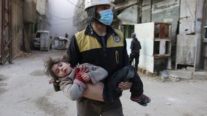 عنصر بالدفاع المدني بالغوطة يحمل طفلة مصابة جراء القصف- الأناضول