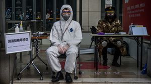 موظفون أمام مركز تجاري لفحص القادمين خشية الإصابة بكورونا في الصين- جيتي