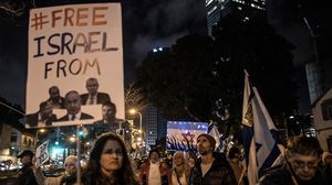 إسرائيلية ترفع صورة أعضاء حكومة نتنياهو على لافتة تقول حرروا إسرائيل من هؤلاء- الأناضول