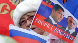 امرأة مسنة في سيفاستوبول ترفع علما يحمل صورتي زعيمي روسيا - أ ف ب