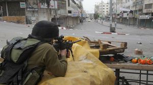 أحد الجنود الإسرائيليين يوجه سلاحه للمارة في الخليل - ا ف ب