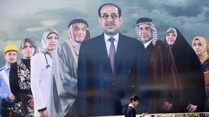 عراقي  يمر أمام ملصق ضخم لقائمة نوري المالكي - ا ف ب