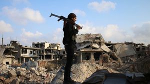 مقاتل من المعارضة في سوريا يقف على ركام الحرب- جيتي
