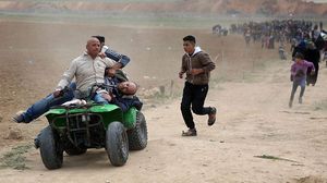 شاب يقوم بإخلاء المصابين على متن دراجة قرب الخط العازل- وكالة شهاب