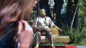 التمثال يجسد واينستين مرتديا ثوب حمام وهو يجلس على أريكة ذهبية ويمسك في يده الأوسكار - جيتي