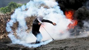 فلسطيني يرمي قنبلة غاز على قوات الاحتلال- الأناضول