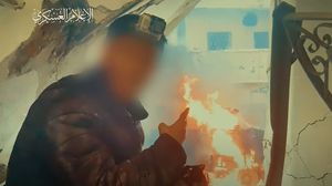 عنصر من القسام يلتقط صورة مع دبابة متفحمة بعد تدميرها بقذيفة في حي الشجاعية- إعلام القسام