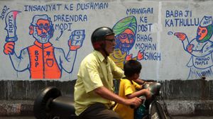 مواطن هندي يمر بجانب رسوم ساخرة للمرشحين - أ ف ب