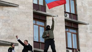 مواطن أوكراني يرفع علم روسيا على منشأة حكومية أوكرانية - أ ف ب