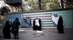 إيرانيون يلتقطون صورا أمام جدارية تصف أمريكا بـ"الشيطان الأكبر" - أ ف ب