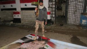 مقاتل من المعارضة يدوس على صورة رئيس النظام السوري في معبر نصيب - الأناضول