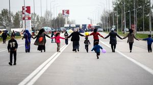 لاجئون يعقدون أيديهم لإغلاق إحدى الطرق شمال اليونان احتجاجا على إغلاق الحدود مع مقدونيا- أ ف ب