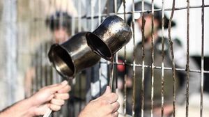 أسير فلسطيني يرفع أواني الشراب بوجه جنود الاحتلال في أحد المعتقلات- إسنا