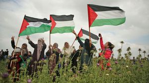 سيدات فلسطينيات في غزة يرفعن الأعلام الفلسطينية قبالة الخط الفاصل- جيتي