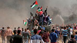 شبان فلسطينيون خلال استقدام إطارات للمنطقة العازلة في مسيرة العودة- جيتي