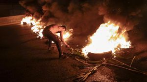 متظاهر لبناني مناهض للحكومة يحرق إطارات لسد الطريق السريع الساحلي شمال العاصمة بيروت- جيتي