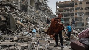 طفل من غزة يجمع أغراضا من ركام منزله الذي دمره الاحتلال- الأناضول