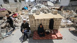 عائلة فلسطينية تجلس على ركام منزلها شمال قطاع غزة- الأناضول