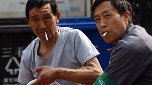 عاملان صينيان يدخنان اثناء العمل في بكين - أ ف ب