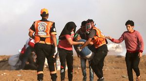مسعفون يحملون شابا مصابا خلال مسيرة العودة بغزة- جيتي