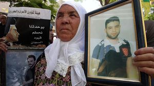 والدة أسير فلسطيني ترفع صورته في فعالية تضامنية مع الأسرى بالضفة الغربية- جيتي