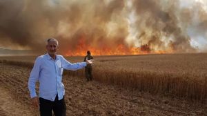 مستوطن بمحيط غزة يقف أمام حقل قمح التهمته النيران بفعل الطائرات الورقية- تويتر
