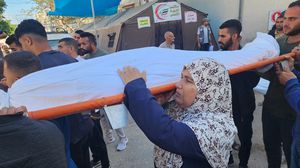 فلسطينية تحمل ابنها الشهيد على كتفها قبل دفنه- الأناضول